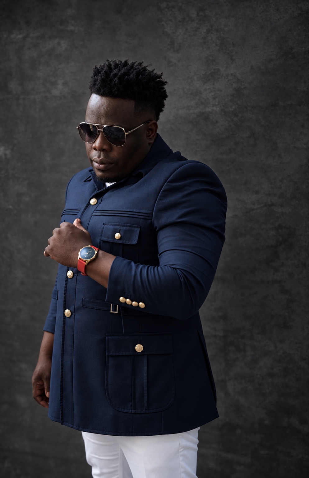 J Ross in a navy blazer against a dark studio wall